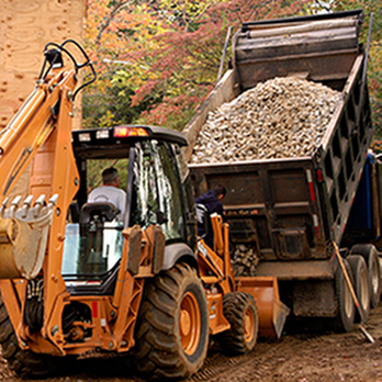 A construction vehicle loading gravel from a truck at a Dahme Construction site in San Jose.